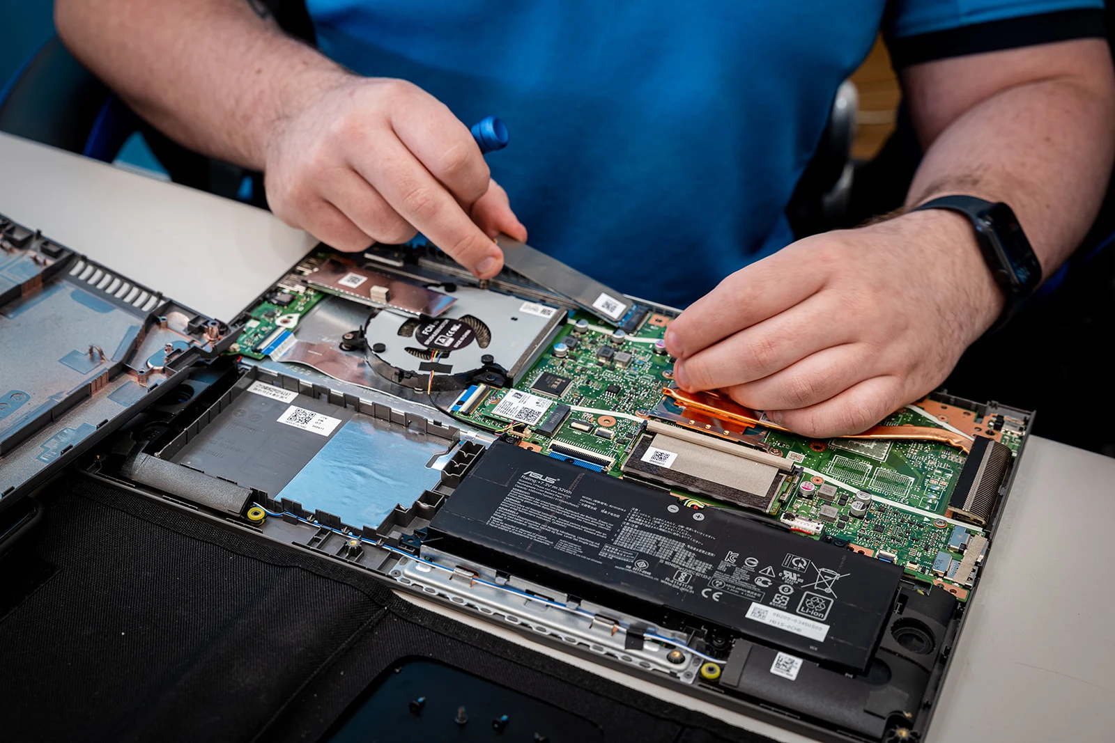A Bay IT technician working on an open laptop at the repair bench