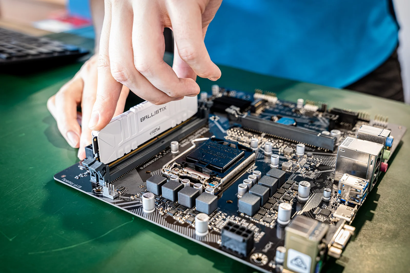 A Bay IT technician installing memory in a desktop motherboard at the workbench