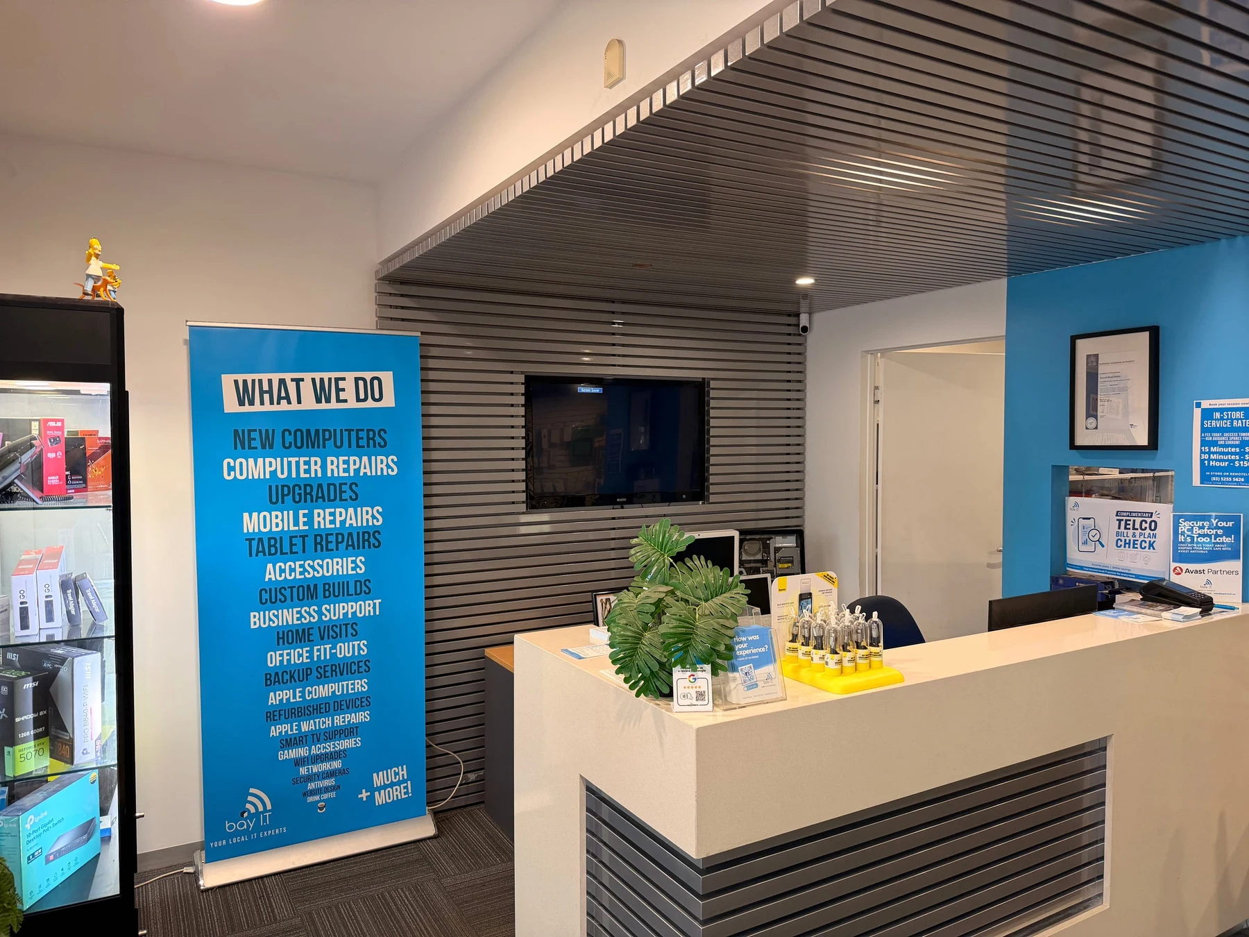 The front counter of the Bay IT Ocean Grove shop, beside a banner listing its services