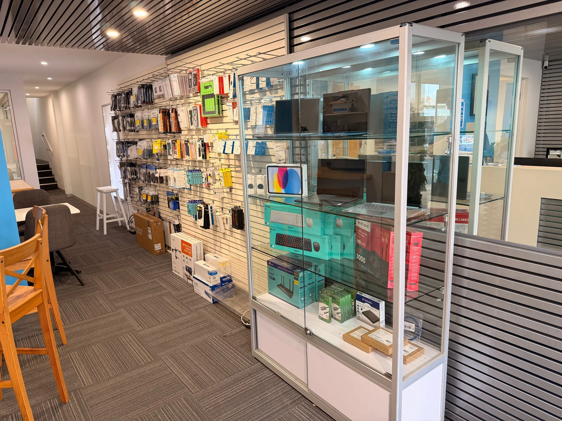 Phone cases, chargers and accessories on the wall of the Bay IT Ocean Grove shop, beside a cabinet of laptops